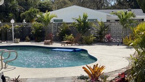 A swimming pool with a tiled deck, surrounded by palm trees and various plants. - Spacious two-bedroom apartment with private, heated pool (near beaches) (St. Petersburg)