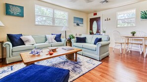 A living room with two light green sofas, a wooden coffee table, and a dining area with a white table and chairs. - Spacious two-bedroom apartment with private, heated pool (near beaches) (St. Petersburg)