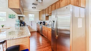 A modern kitchen with wooden cabinets, a stainless steel refrigerator, and a granite countertop. - Spacious two-bedroom apartment with private, heated pool (near beaches) (St. Petersburg)