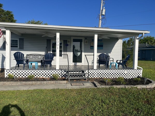 A single-story house with a porch, numbered 2001, featuring outdoor seating with chairs and tables. - Oceanside Village 4 bedroom home 4 minute walk to the beach HappyDaze (Myrtle Beach)