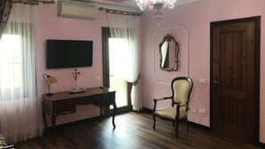 Ein Zimmer mit einem Holztisch, einem Sessel, einem Fernseher, einem Spiegel und einer Chandelier.