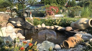 Ein Garten mit Teich, Steinen und Blumen.