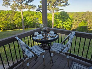 A deck with a table and two chairs, surrounded by a railing, overlooking a forested area. - Apartment, Mountain View/Personal Deck Bikers welcome. Mins to DT Eureka Spgs. (Eureka Springs)