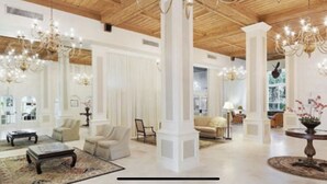 Un vestíbulo amplio con techos altos, candelabros y una columna central.
