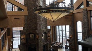 A spacious lobby with a high ceiling, stone fireplace, and large windows offering views of the outside.