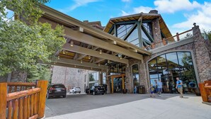A modern building with a stone facade, large windows, and a covered entrance area.