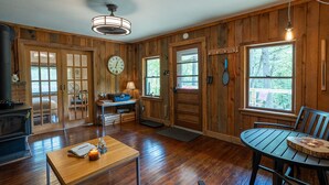 A wooden interior with a dining table, a clock, and a fireplace. - Remote Waterfall Cabin at Swiftwater Acres (Millrift)