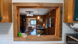 A kitchen with wooden cabinets, a built-in stove, and a window overlooking the living area. - Remote Waterfall Cabin at Swiftwater Acres (Millrift)