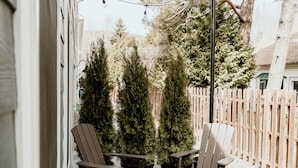 Een terras buiten met Adirondack-stoelen, een tafel en een decoratieve lantaarn.