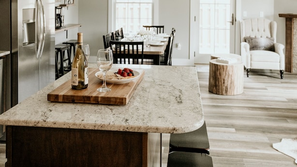 Een moderne keuken met een centraal eiland, houten stoelen en een eettafel.