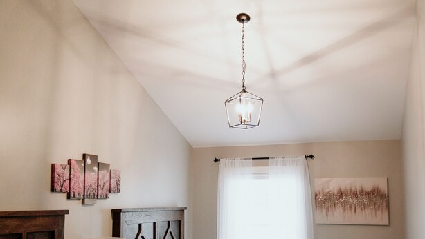Une chambre avec deux lits, un lustre, des œuvres d’art et une fenêtre avec des rideaux.