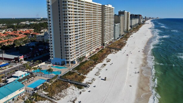 Ein Hochhaus-Hotel mit zahlreichen Balkonen, einer Strandlage und einem Schwimmbad.