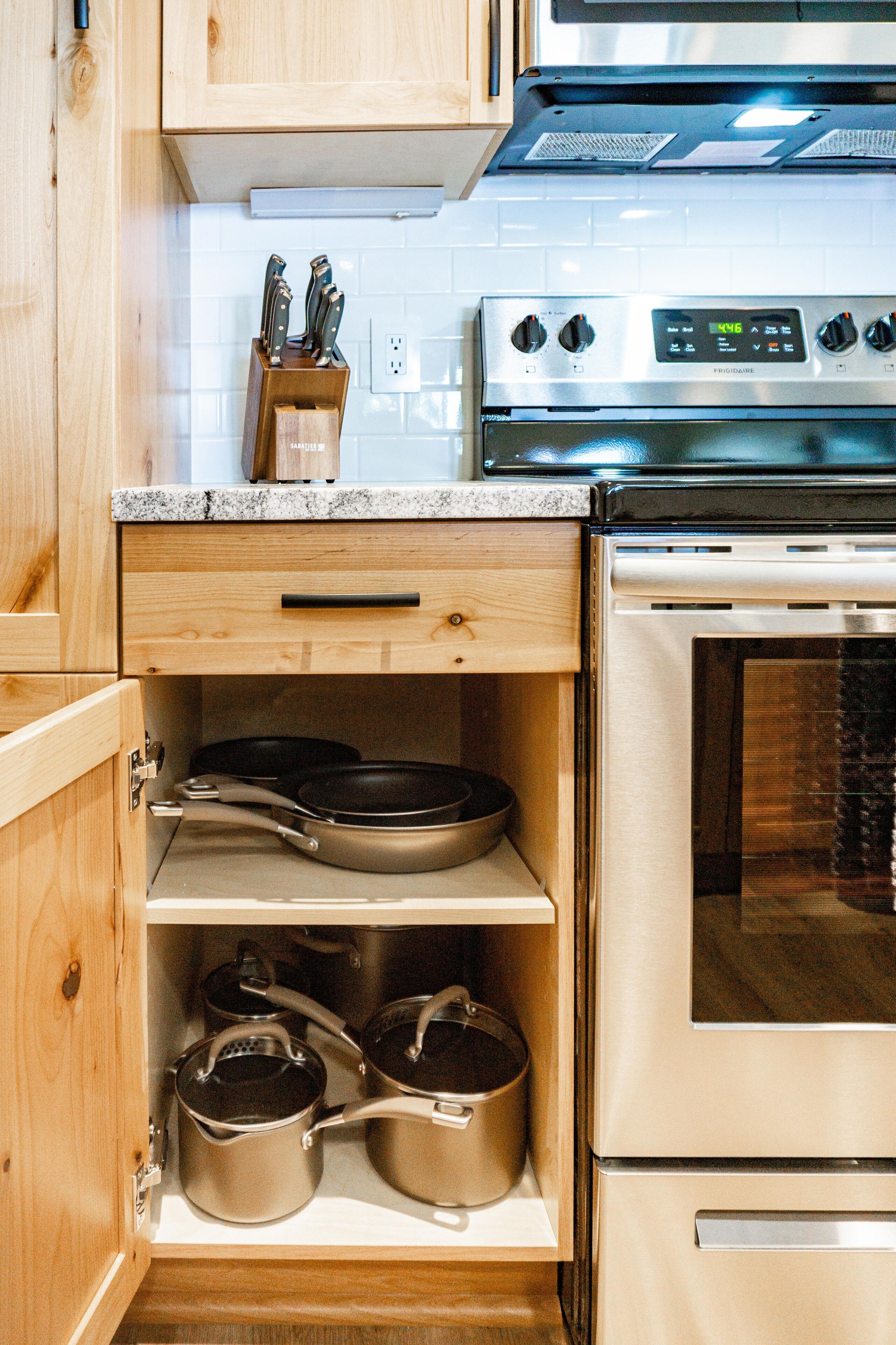 Una cocina con armarios de madera, un horno de acero inoxidable y una encimera con un bloque de cuchillos.