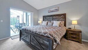 Une chambre à coucher avec un lit, des tables de chevet, une fenêtre et une vue sur l’extérieur.