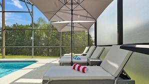 Un espace de détente aménagé au bord de la piscine, avec des chaises longues et un parasol.
