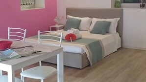A room with a wooden ceiling, a bed with pillows, a table with chairs, and a window with curtains. - Ciclamino Apartment Residenze Lariane (Colico Piano)