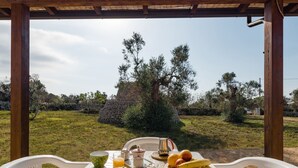 Ein Tisch draußen gedeckt mit Frühstücksgebäck, Blick auf die Landschaft, und eine Holz-Pergola.
