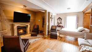 A cozy living room with a fireplace, a television, and comfortable seating. - The Watermark Suite (Drumheller)