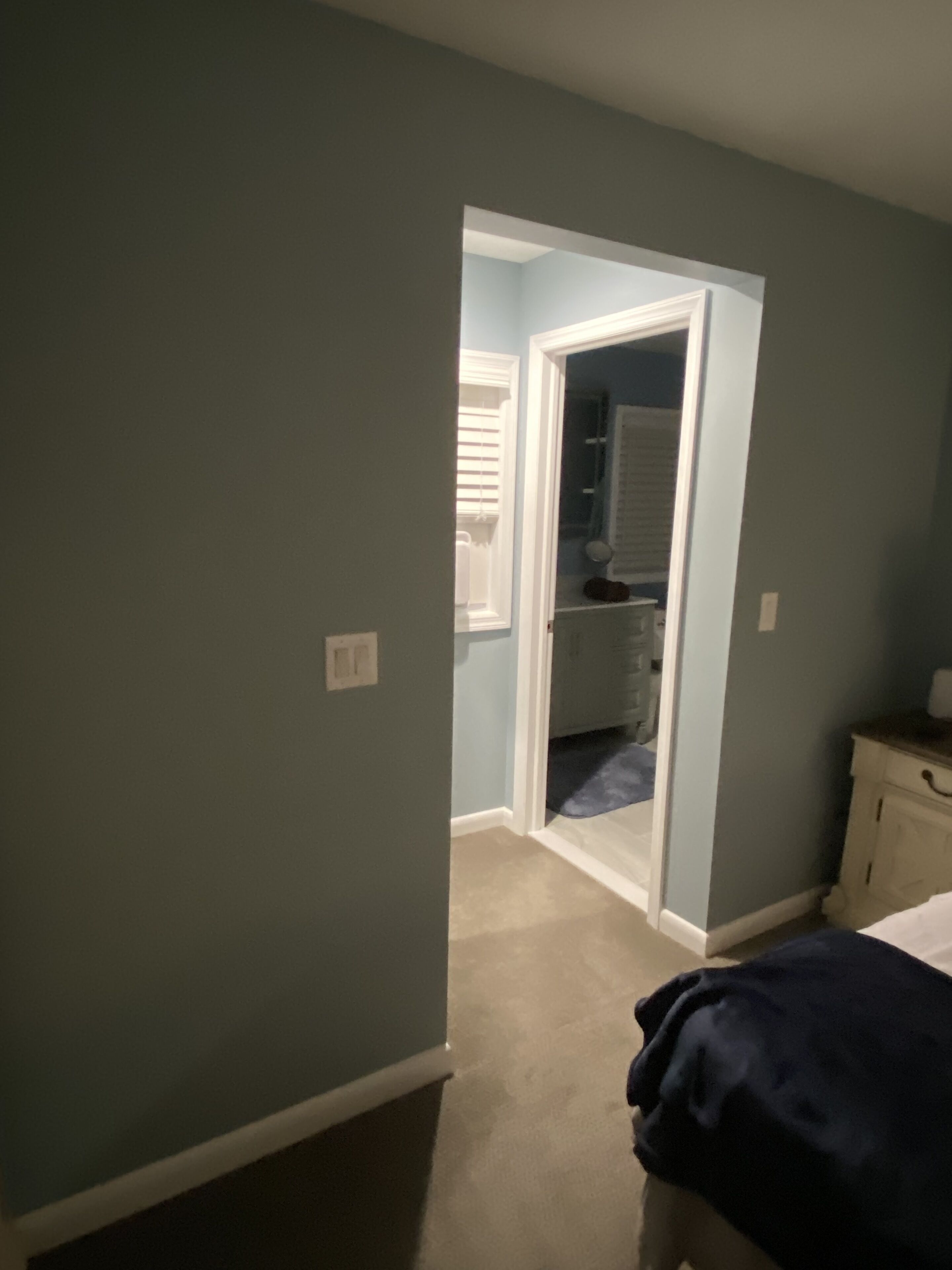 Une chambre à coucher comprenant un lit, une commode et une porte donnant sur une salle de bain.