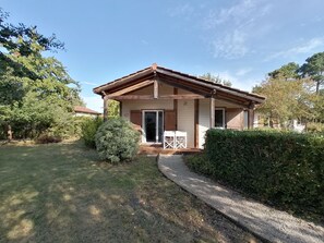 A single-story house with a covered porch, a door, and a small seating area with chairs.