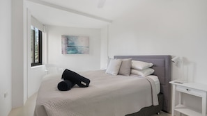 A minimalist bedroom with a bed, a bedside table, a lamp, and a painting on the wall.