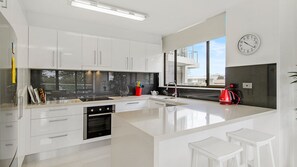 A modern kitchen with white cabinetry, a large island, and a view through the window.
