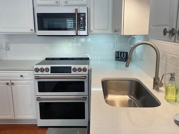A kitchen with white cabinets, a stainless steel sink, and a built-in oven.