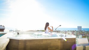 A woman relaxing in a hot tub with a city view. - Jacuzzi Pool Spa Ocean View 4bd 5ba House (El Sauzal)