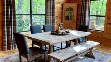 A wooden cabin interior with a dining table, chairs, and a bench.