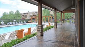 A covered outdoor area with a pool, lounge chairs, and stone pillars.