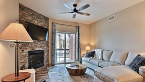 A living room with a fireplace, a ceiling fan, a sofa, a coffee table, and a lamp.