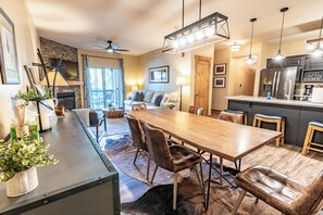 A modern kitchen with a large island, dark cabinetry, and stainless steel appliances.