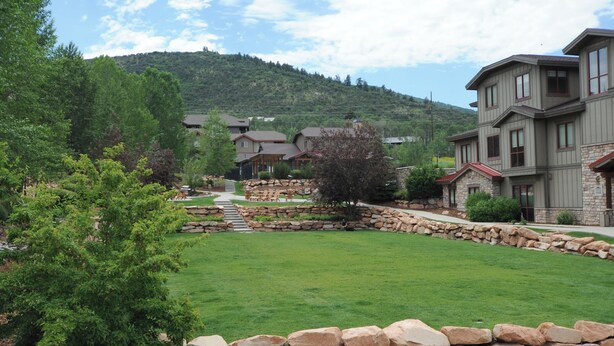A residential area with houses, a stone wall, and a grassy lawn.