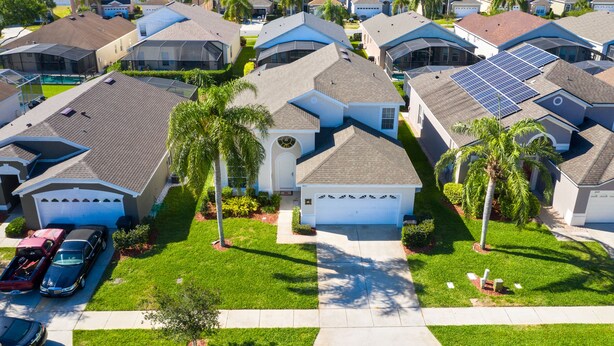 A residential neighborhood with houses, solar panels, and a well-maintained lawn.