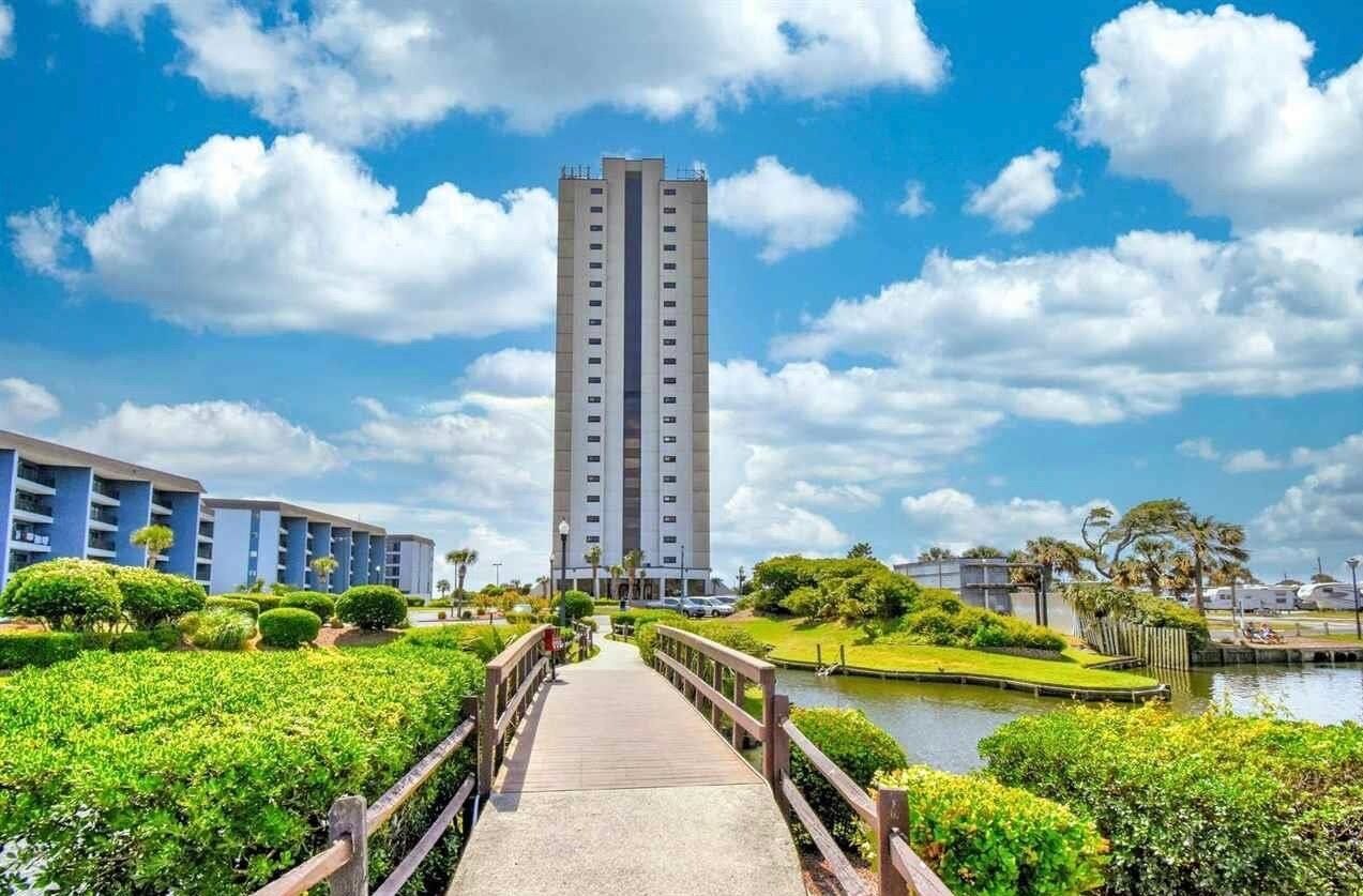 Un grand hôtel doté d’une tour centrale, entouré d’espaces verts aménagés et d’un plan d’eau.