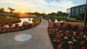 Un sentier qui mène à un plan d’eau, avec un coucher de soleil en arrière-plan.