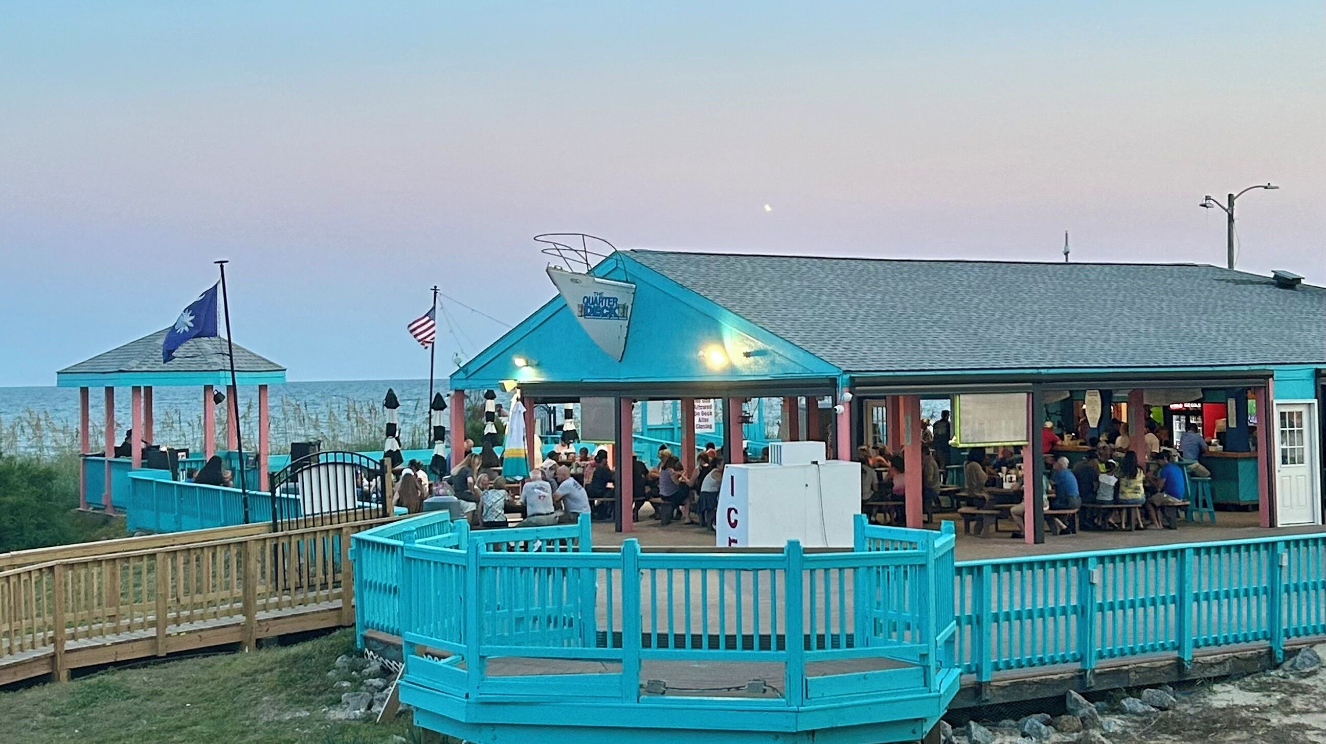 A waterfront restaurant with outdoor seating and a covered area.