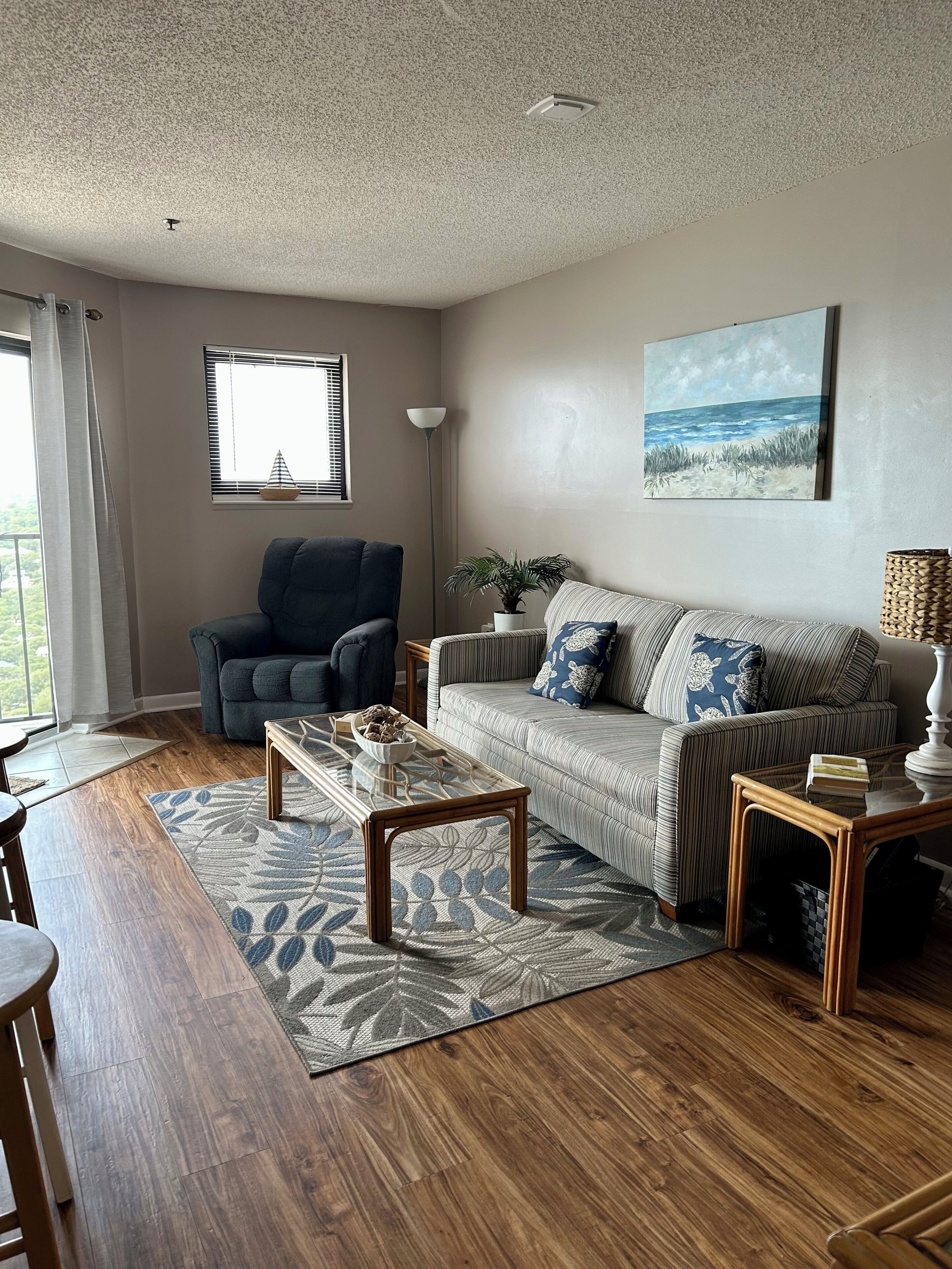 A living room with a sofa, armchair, coffee table, and a painting on the wall.