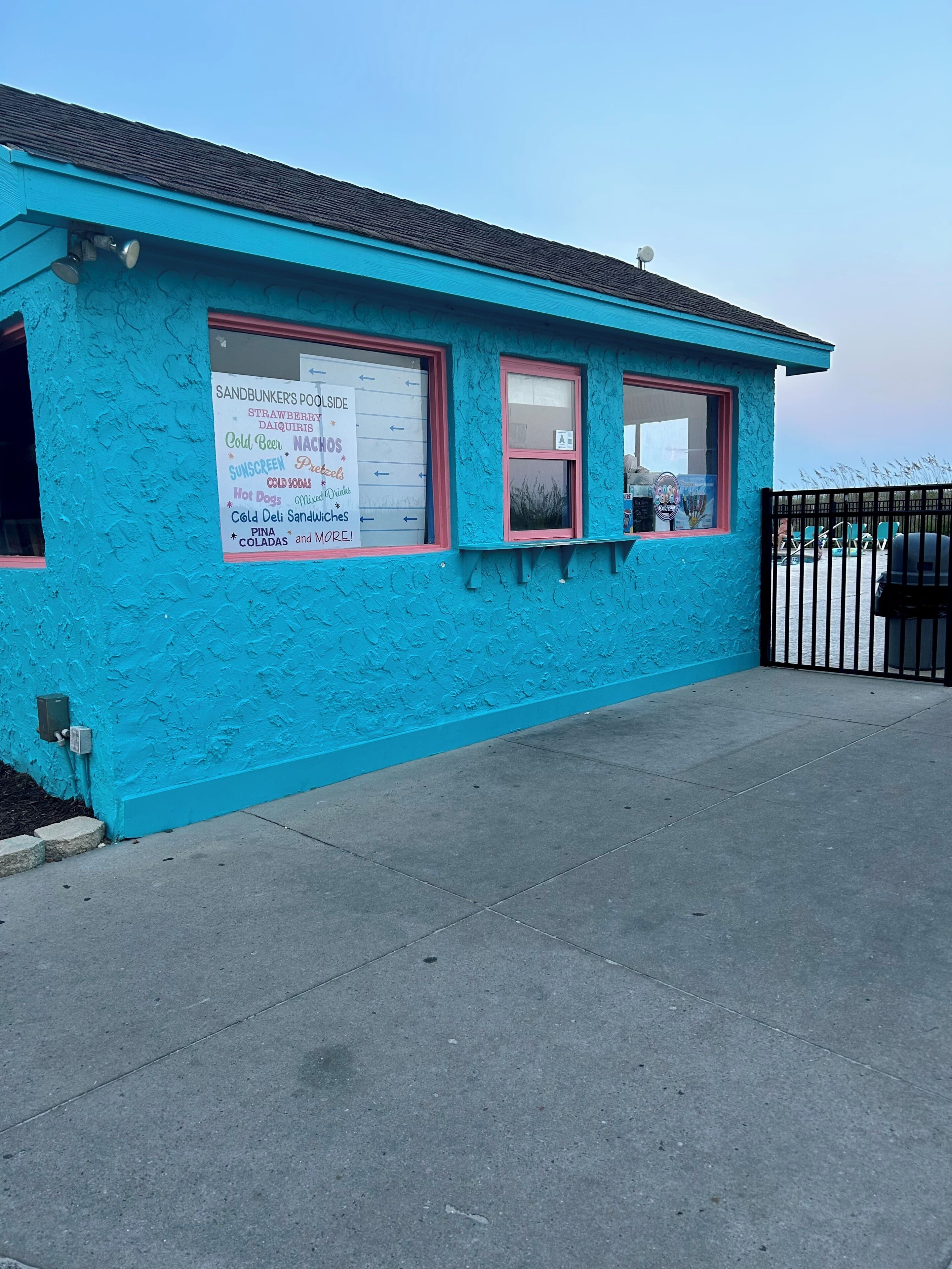 A small building with a blue exterior and a signboard advertising various food and drink items.