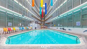 Une piscine intérieure d’une profondeur de 2,4 mètres, entourée de fenêtres et de chaises, et agrémentée de panneaux indiquant une faible profondeur et interdisant la plongée.