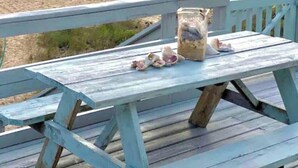 Une terrasse en bois avec une table de pique-nique et un bocal rempli d’en-cas.