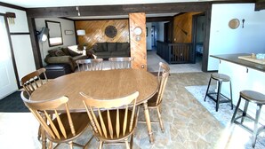 Un coin repas avec une table et des chaises en bois, un ventilateur de plafond et un sol en pierre.