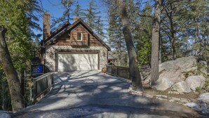 Une cabane avec une façade en pierre, un garage et une terrasse en bois.