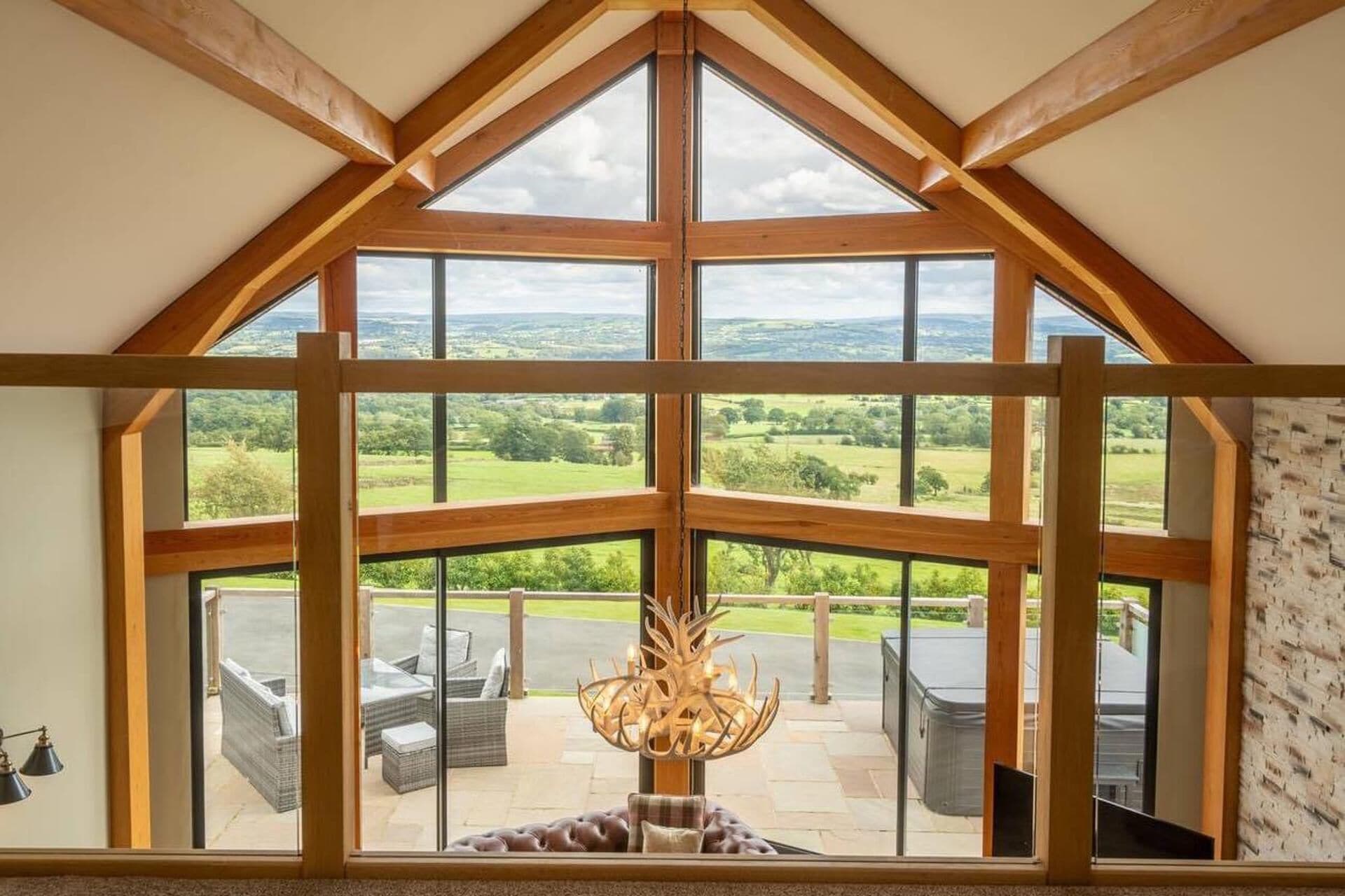 A room with a large skylight, a view of a green landscape, and a patio area with outdoor furniture.