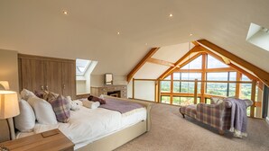 A bedroom with a large bed, a nightstand, a dresser, and a window with a view of the outdoors. - Valley View Lodge Sleeps 8 With Hot Tub (Preston)