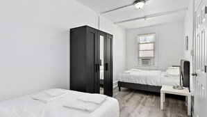 Une chambre d’hôtel moderne équipée de deux lits, d’une armoire, d’un bureau et d’une fenêtre avec des stores.