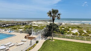 A beachfront hotel with a swimming pool, lounge chairs, and a wooden pier. - Amazing Pool/Oceanfront Views from this Second Floor Condo at Amelia by the Sea! (Fernandina Beach)