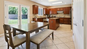 A kitchen with wooden cabinets, a dining table with chairs, and a large island. - Large Family home near Sequoia National Park (Visalia)