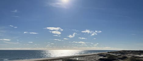 A beach with a clear sky and the sun shining.