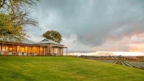 Un edificio de piedra con un porche cubierto y un árbol grande en el frente.